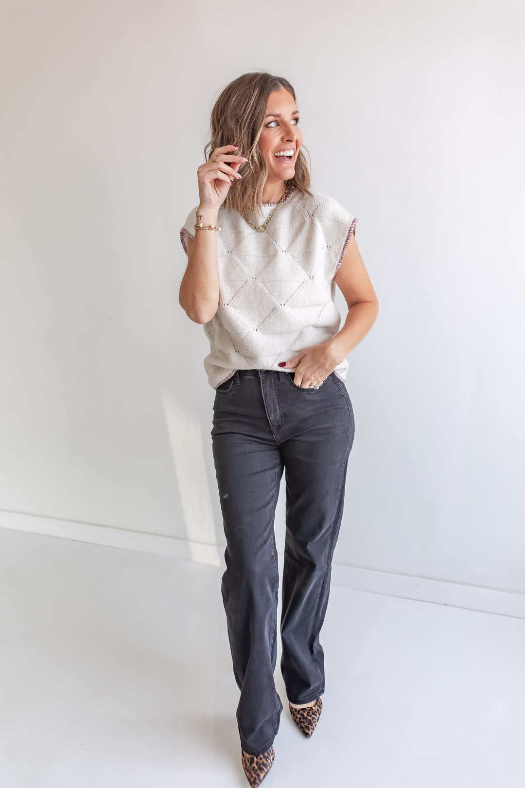 Cream short sleeve sweater with wine stitching paired with black wide leg mica denim jeans.