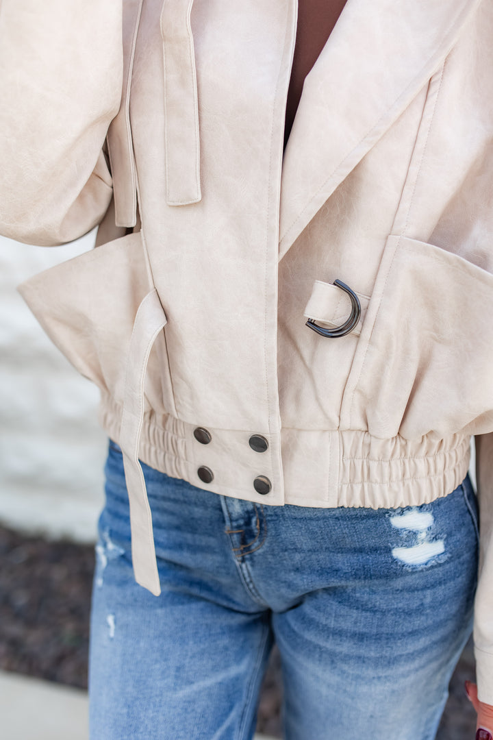 Beige jacket with black buttons worn over a blue denim outfit.