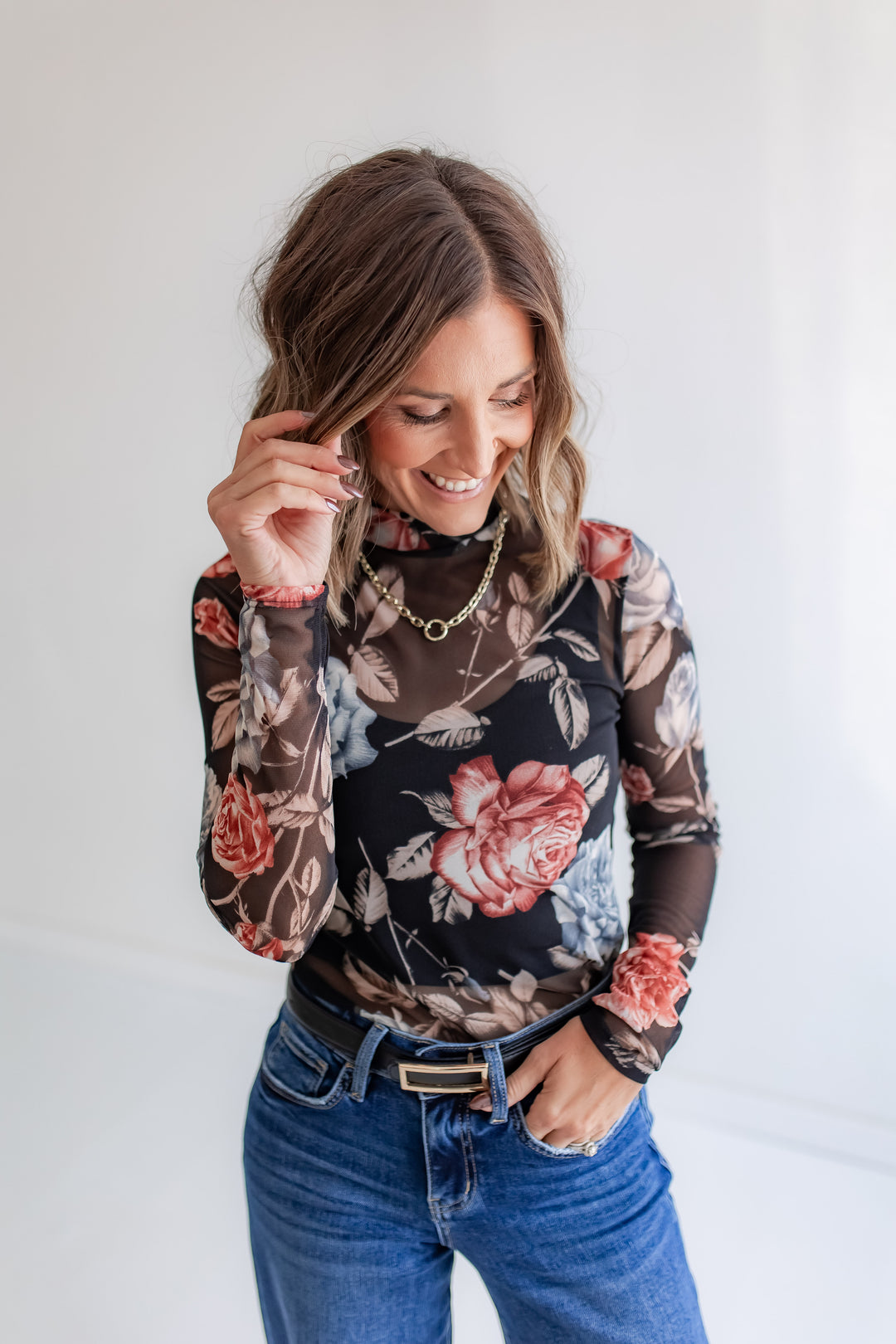 Model wearing a sheer fall floral blouse with long sleeves.