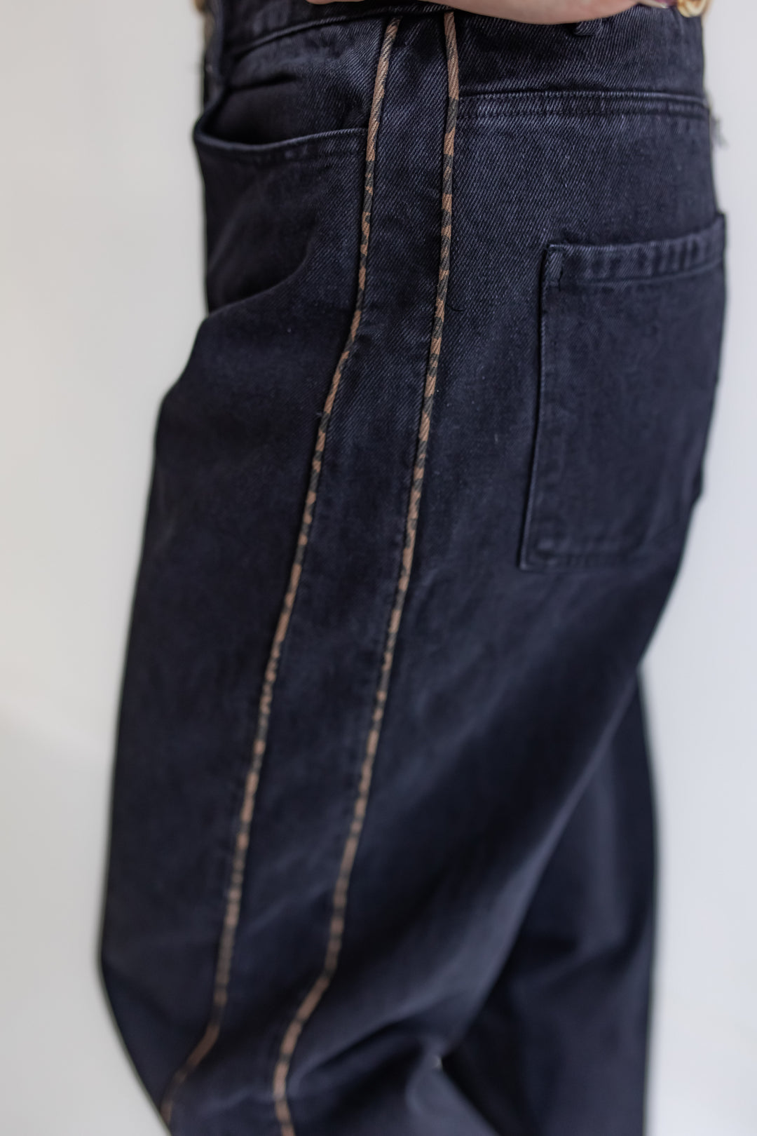 Close up of black barrel jeans with leopard piping on sides. 