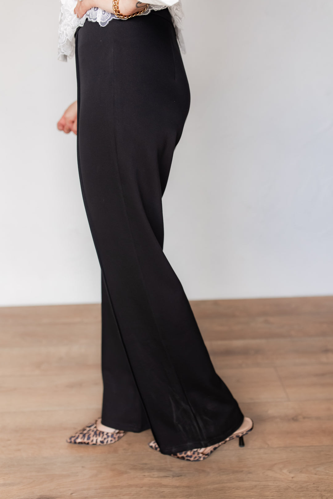 Side view of black flare trousers showing back zipper closure and stretchy fabric