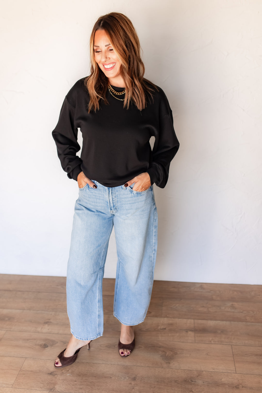 "Woman wearing black knit balloon sleeve pullover with light wash barrel jeans