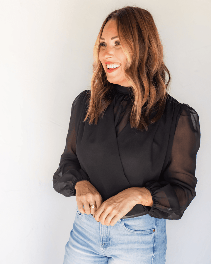 Close-up of black chiffon blouse with gathered high neckline and non-sheer surplice front