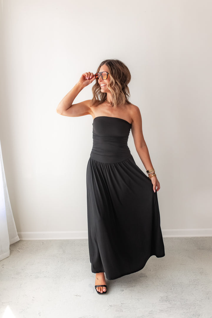 Black strapless maxi dress with soft fabric, drop waist and flowy silhouette styled with sandals