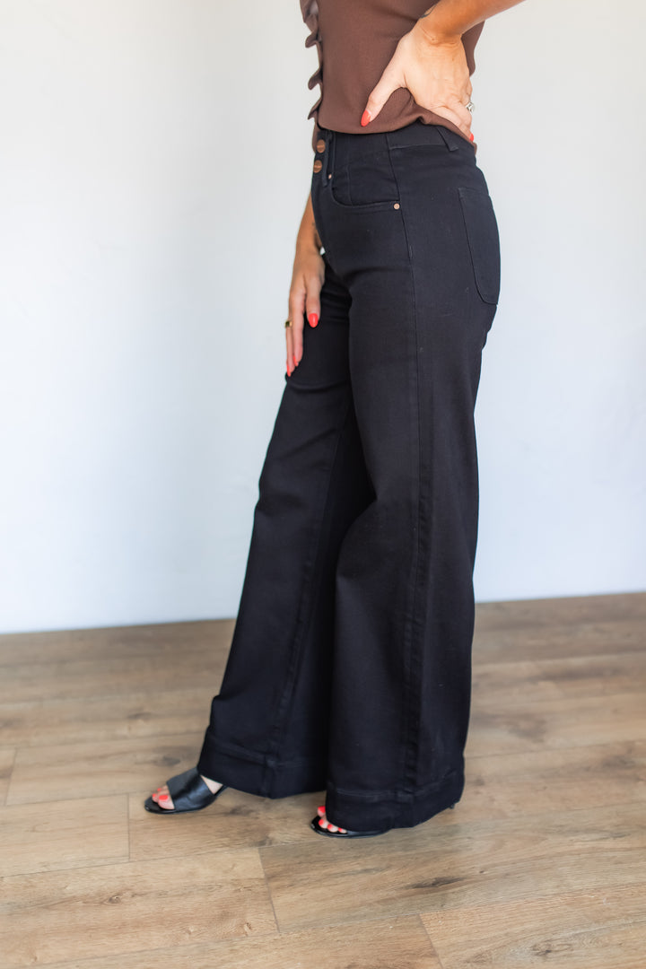Side profile of black high rise wide leg jeans with black sandals