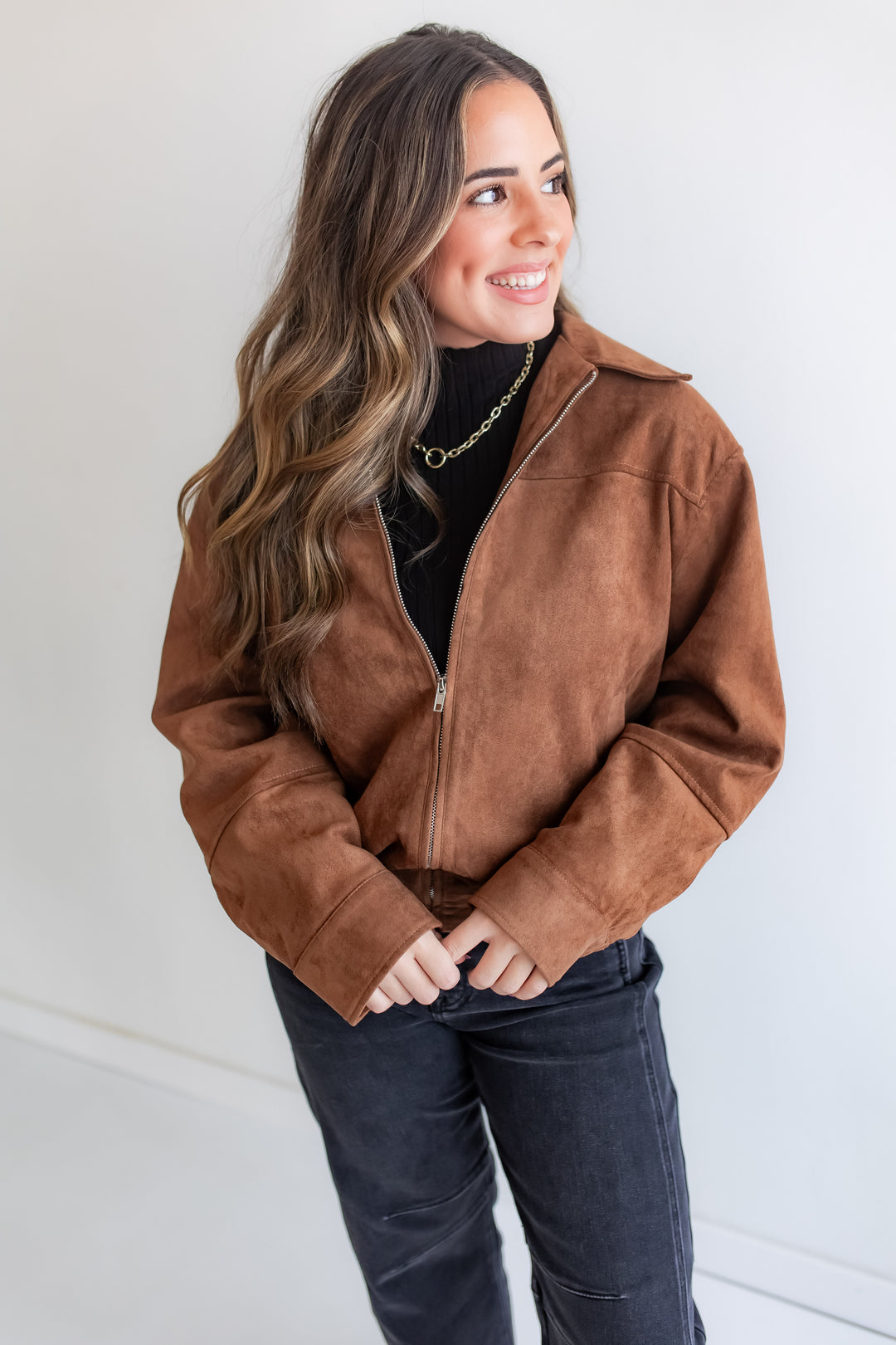 Woman wearing a brown suede jacket against a white background