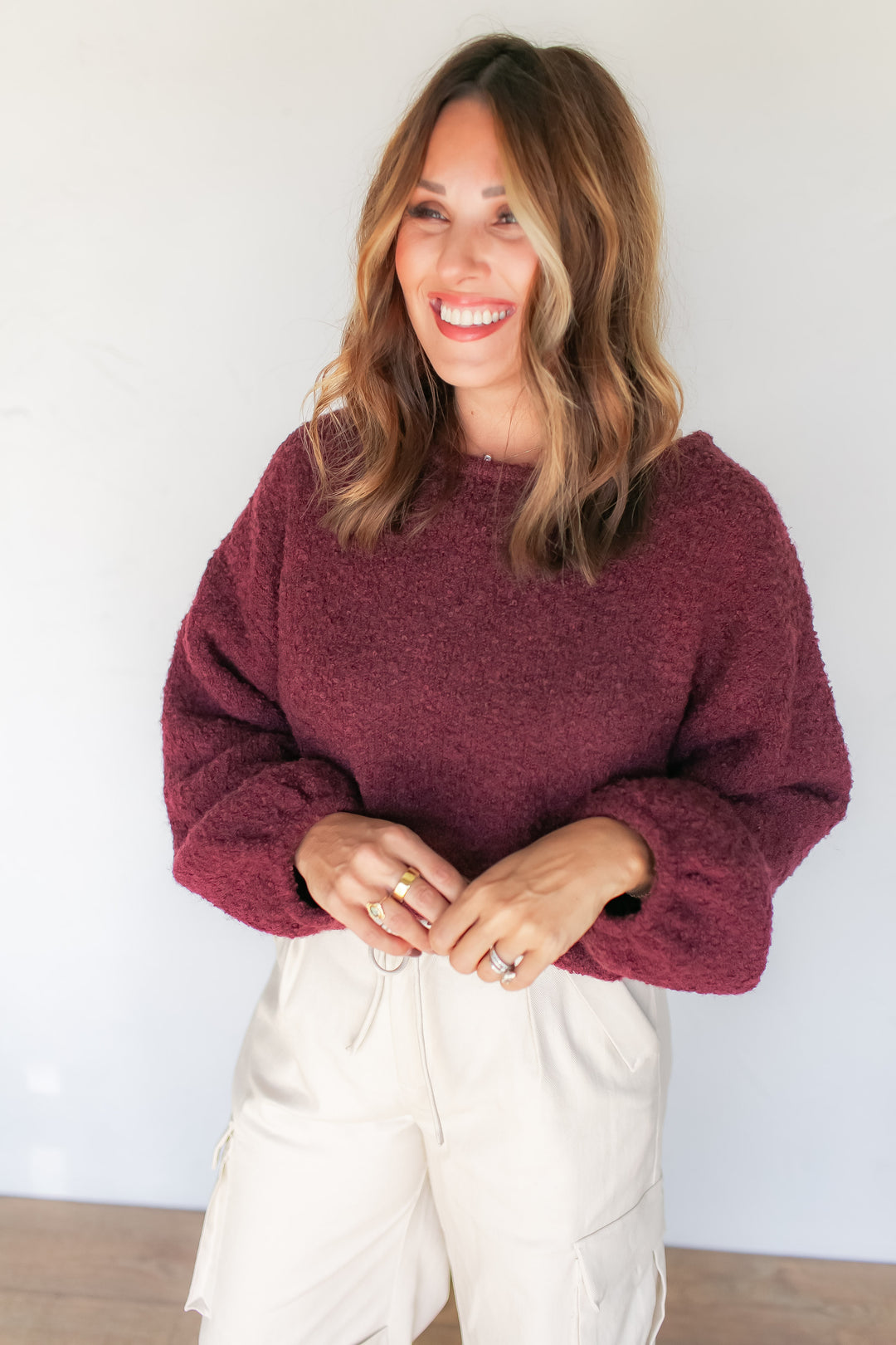 Woman wearing burgundy crewneck sweater with cream trousers