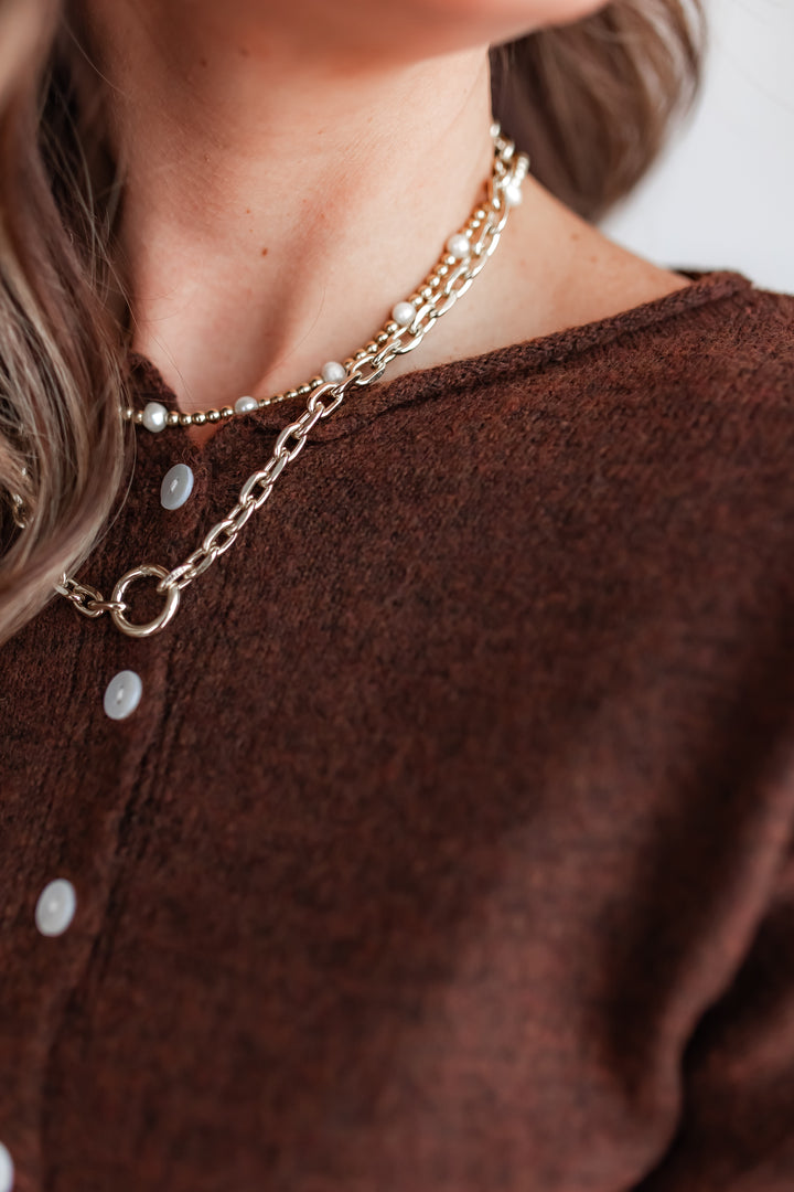 close up of a chocolate brown sweater cardigan with pearly buttons