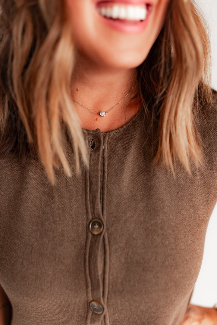 Close-up of a person wearing a brown button-up sleeveless sweater dress