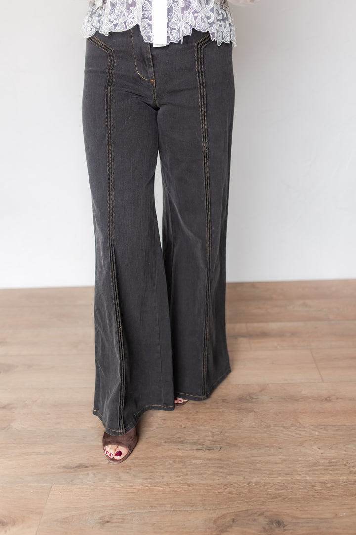Woman wearing charcoal wide leg denim pants with contrast stitching, styled with a lace blouse