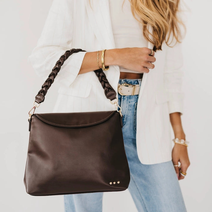 "Woman carrying chocolate brown crossbody bag with braided strap and white blazer