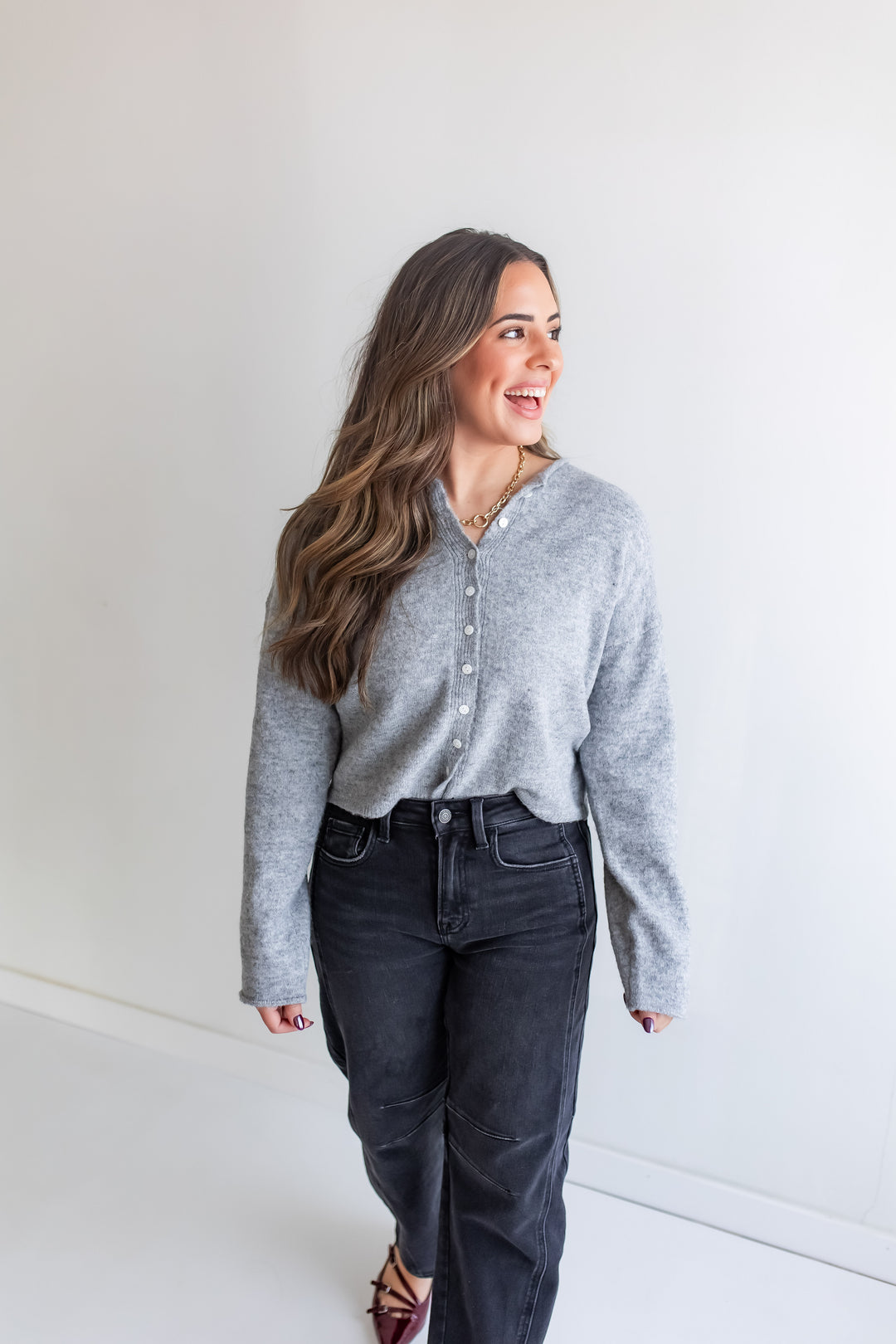 Woman wearing a grey button-up cardigan and dark jeans