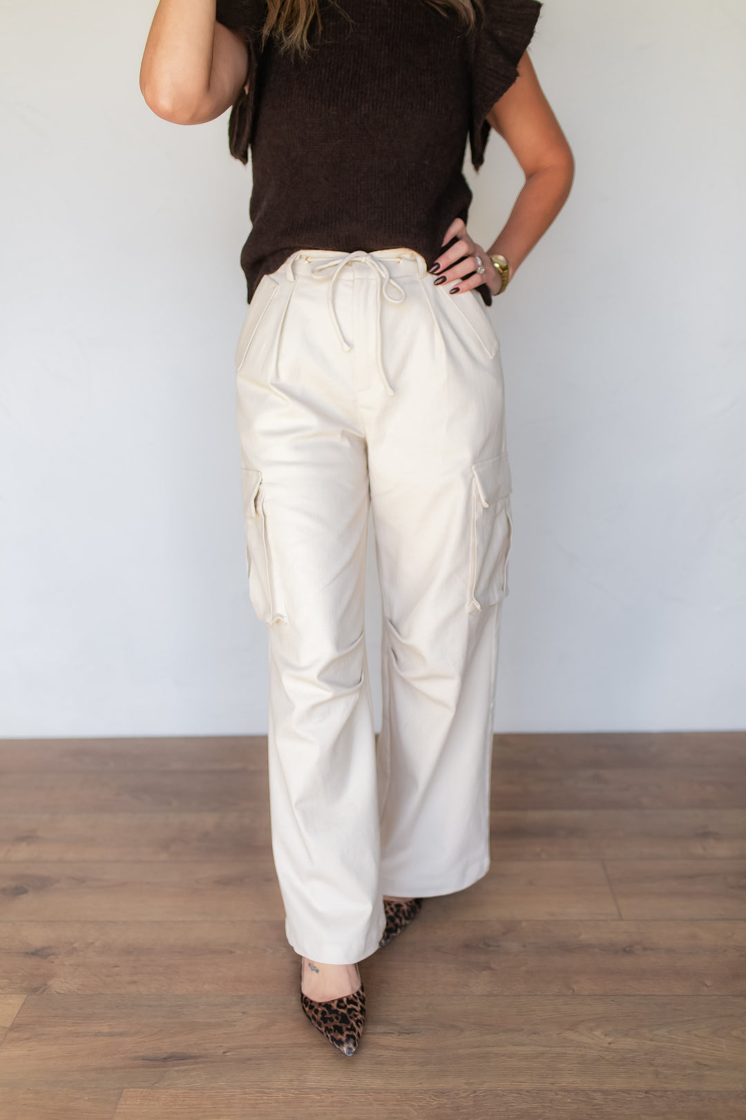 Woman wearing cream cotton-spandex cargo pants with drawstring waist, styled with a brown sweater