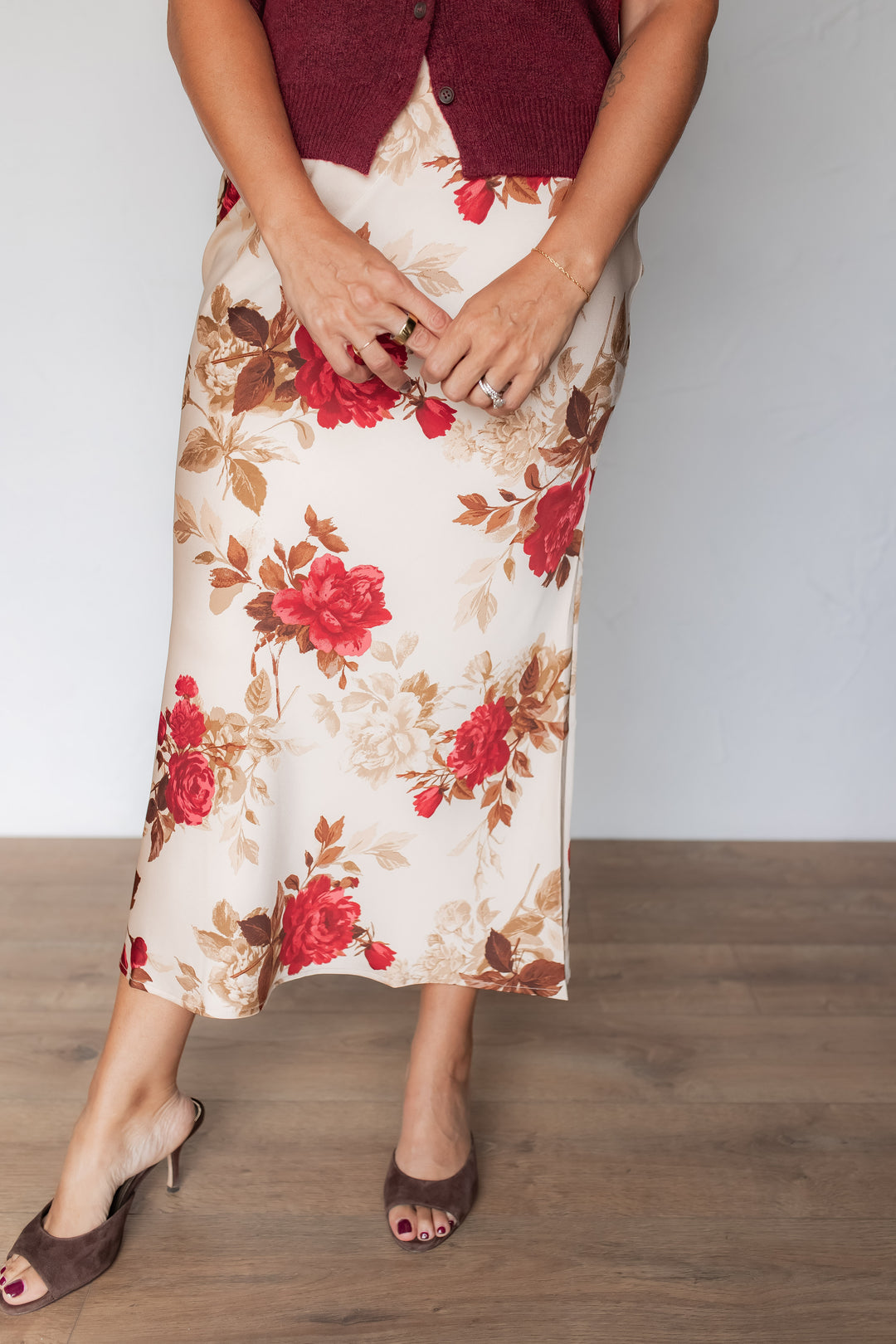 Cream satin midi skirt with red rose floral print, styled with a burgundy cardigan