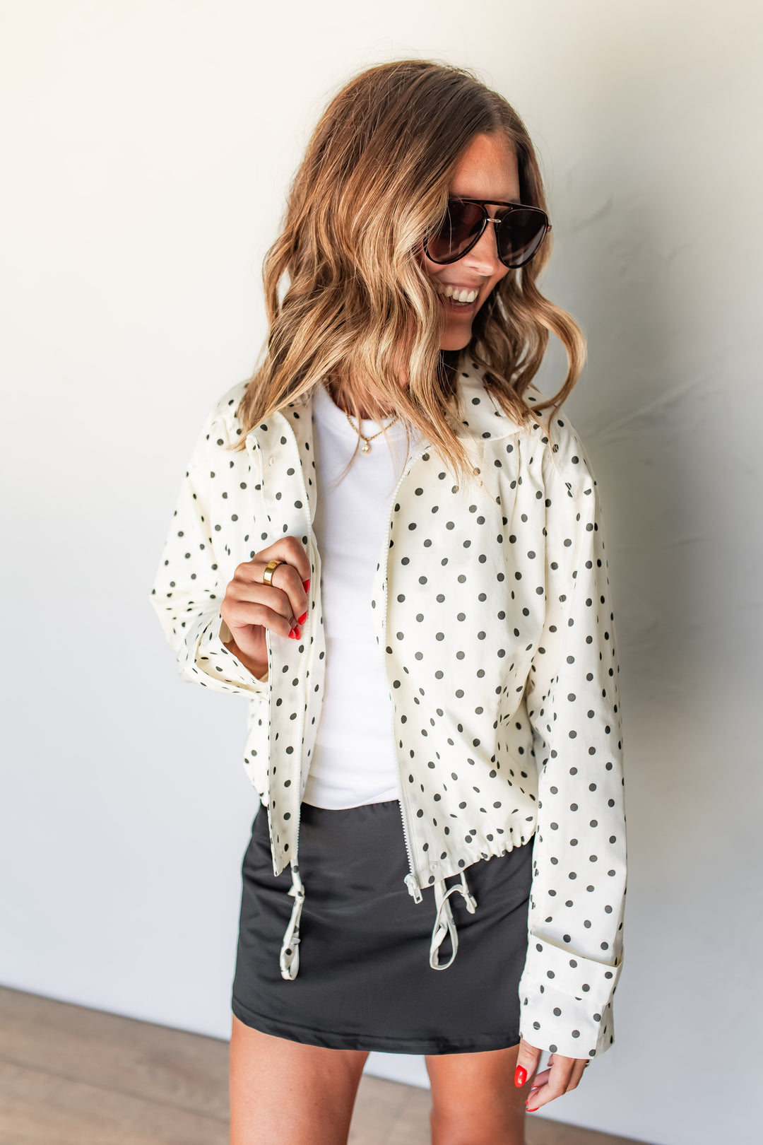 Woman wearing cream polka dot cotton shell jacket over white tee and black skirt