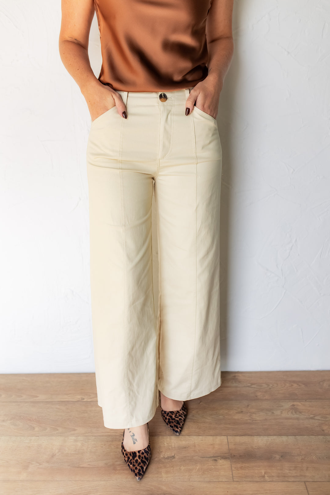 Close-up of front pocket and seam detail on cream tailored pants