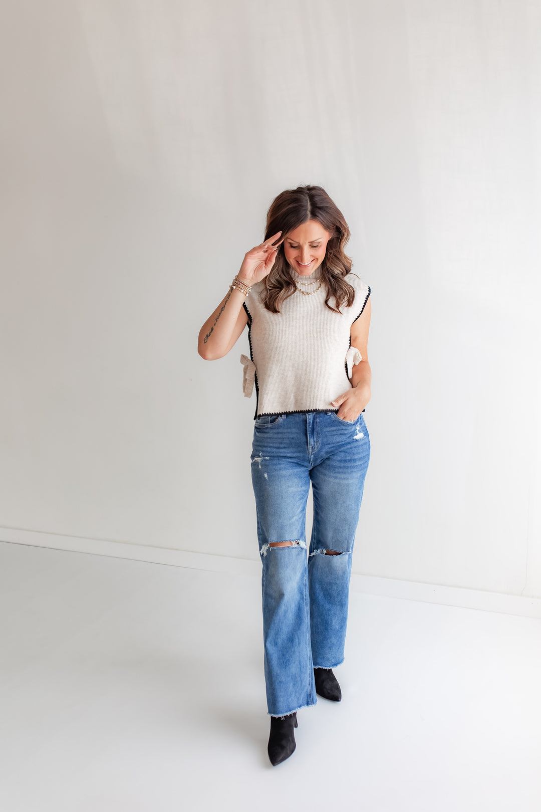 Model wearing a pair of Mica denim with black boots and a sweater. 