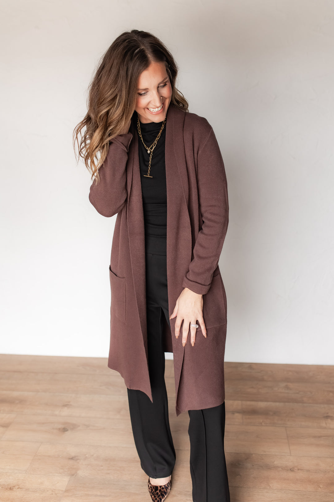 Woman wearing espresso open-front duster cardigan over a black turtleneck and trousers