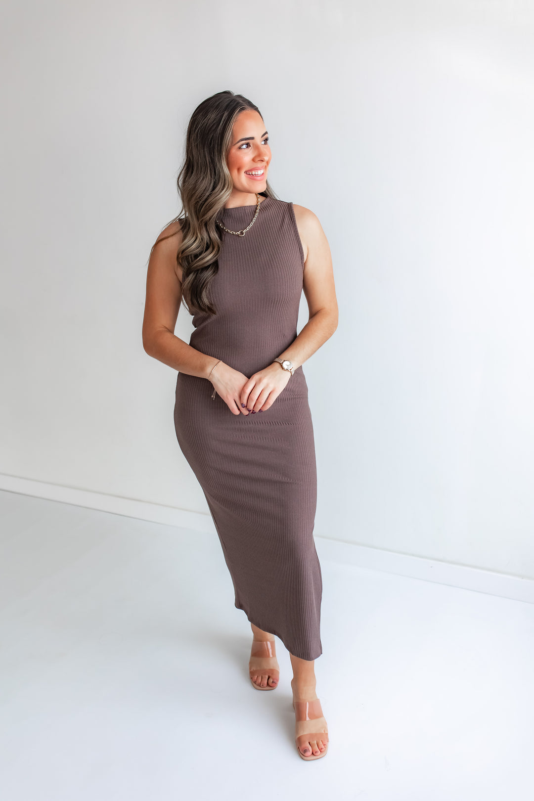 Model wearing a sleeveless mocha color fitted midi dress with heels