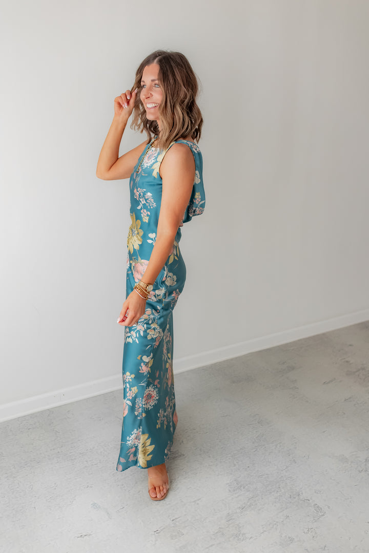 A teal floral satin maxi dress with elegant open back detail. 