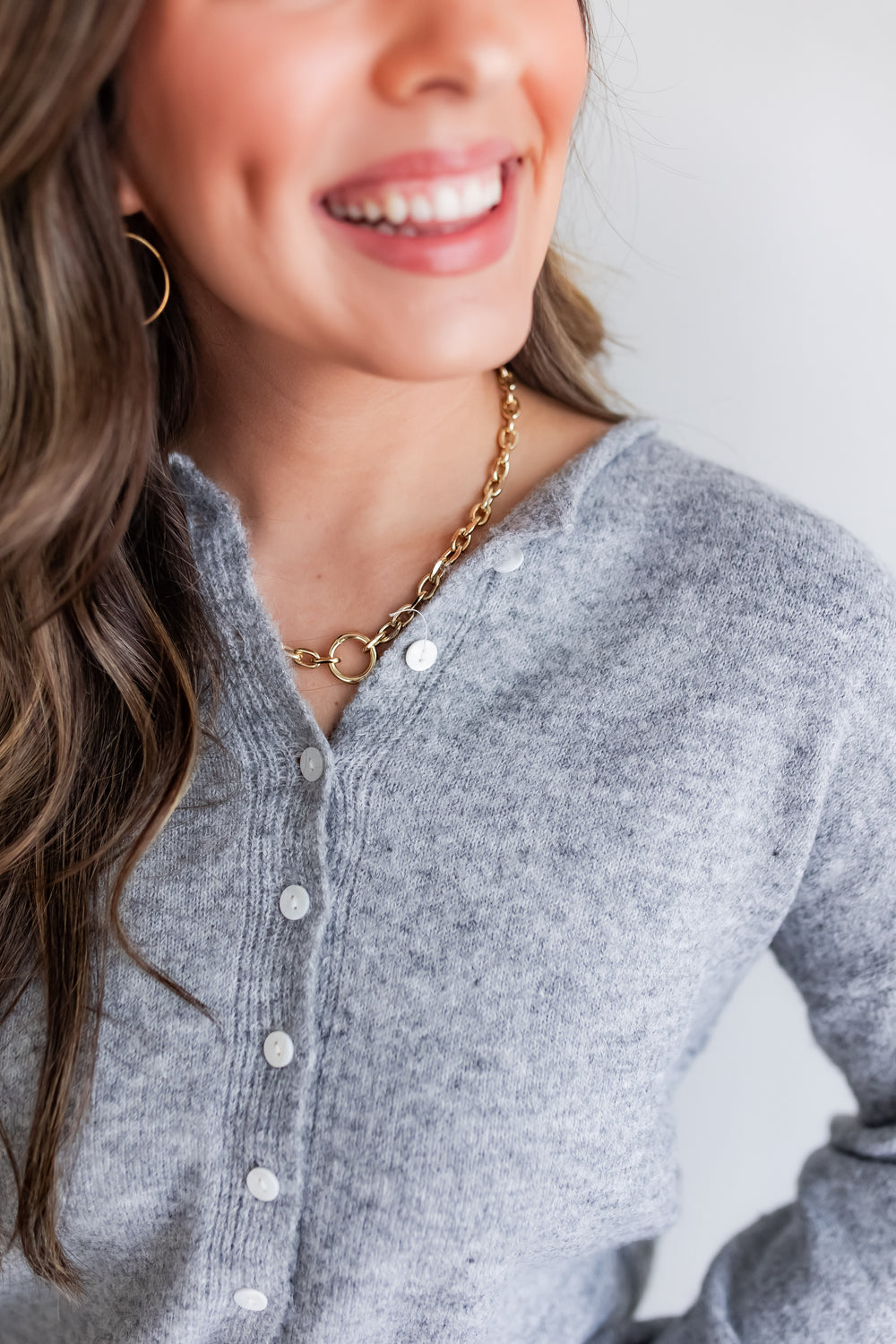 Woman wearing a gray cardigan and gold necklace