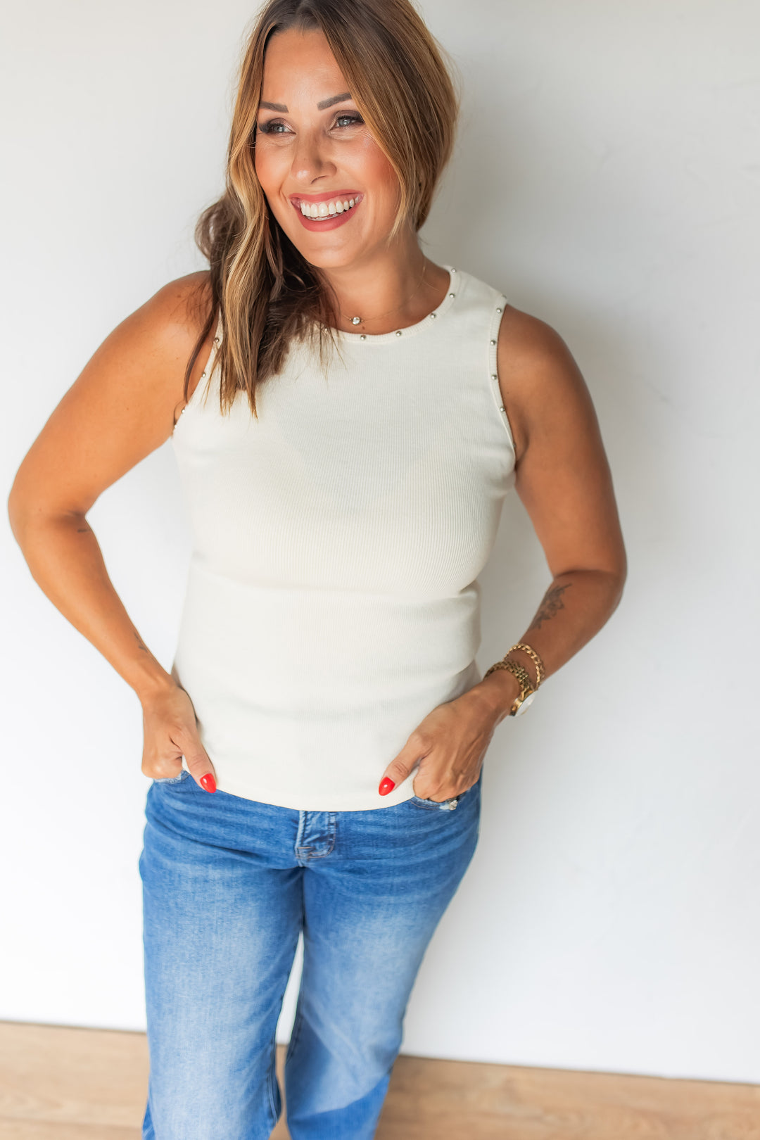 Woman wearing ivory studded ribbed tank with medium wash jeans