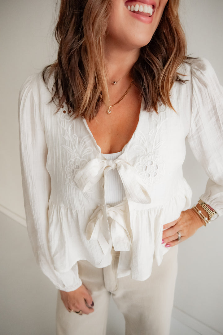 Romantic cream blouse with eyelet details and bow front closure