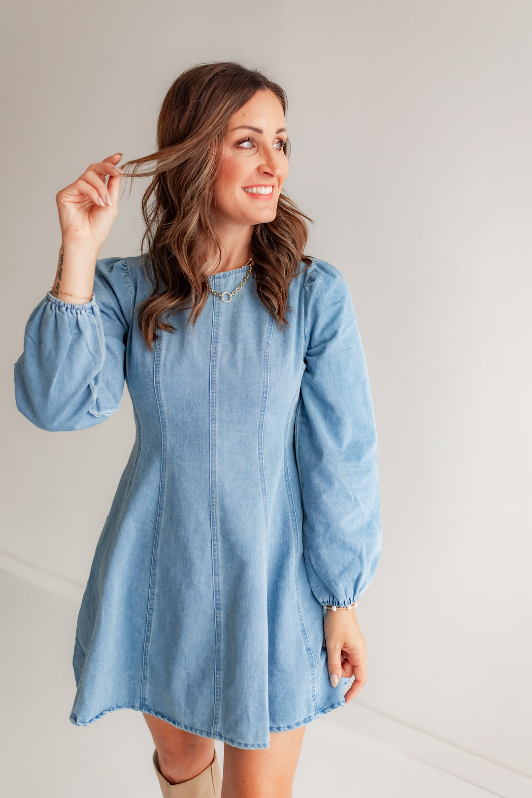 Woman wearing a light blue denim dress with brown boots