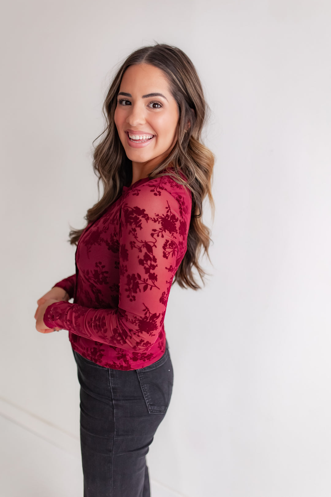 Woman wearing a red floral long-sleeve top against a white background