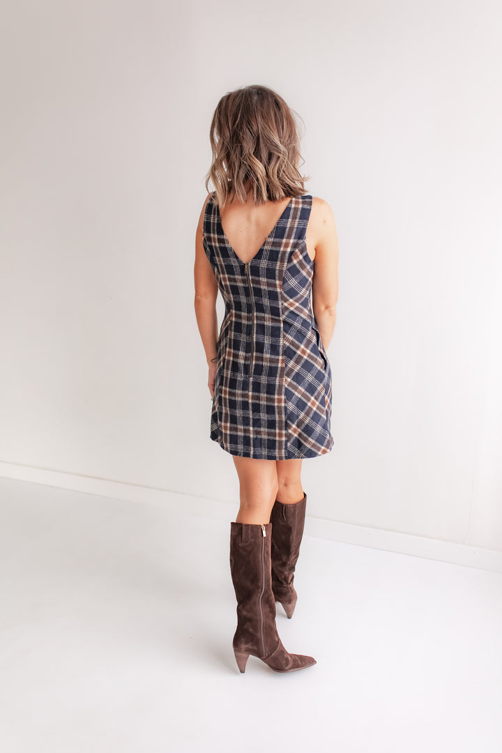 Woman wearing a plaid dress and brown knee-high boots on a white background