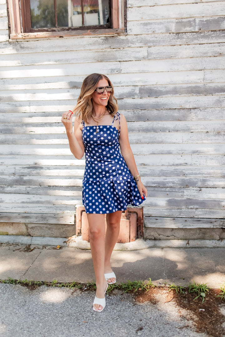 Woman wearing navy polka dot mini dress styled for casual summer day
