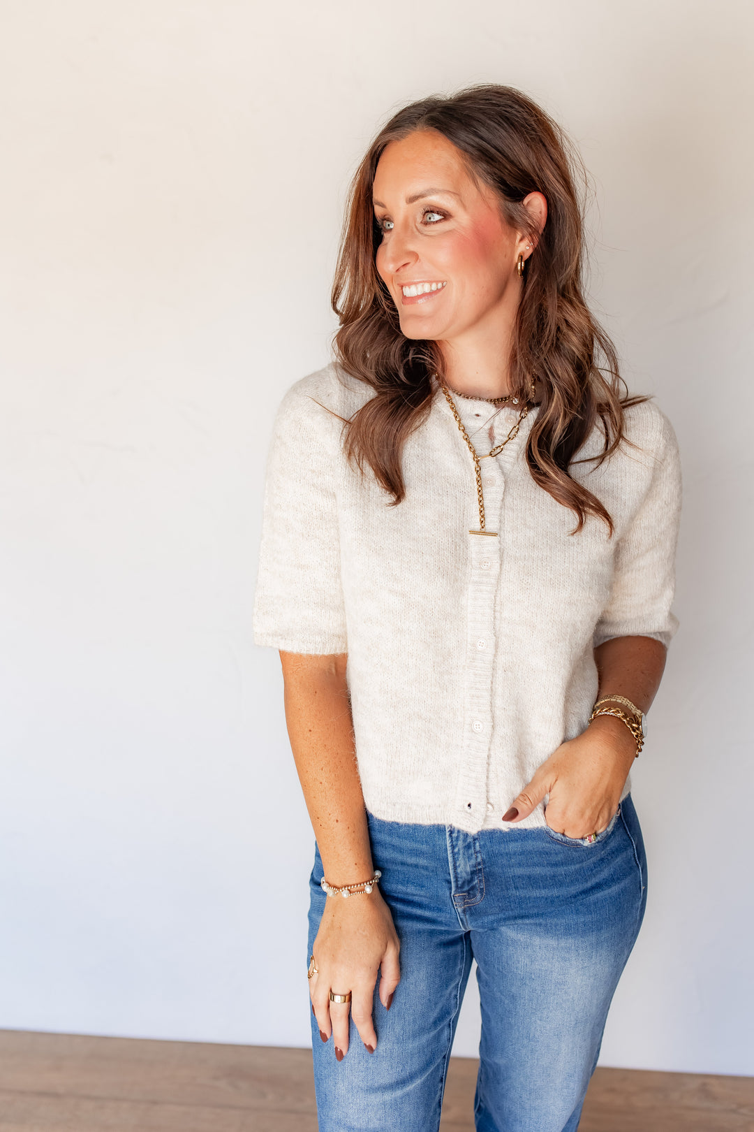 Close-up of oatmeal button-front knit sweater with gold layered necklace