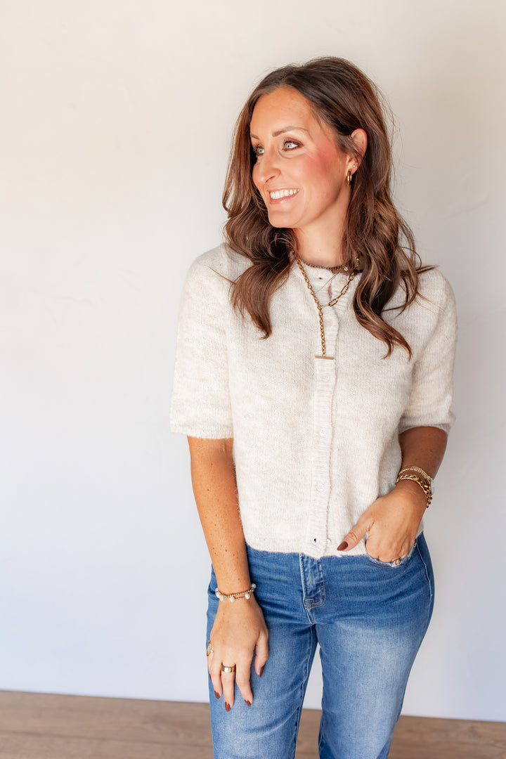 Close-up of oatmeal button-front knit sweater with gold layered necklace