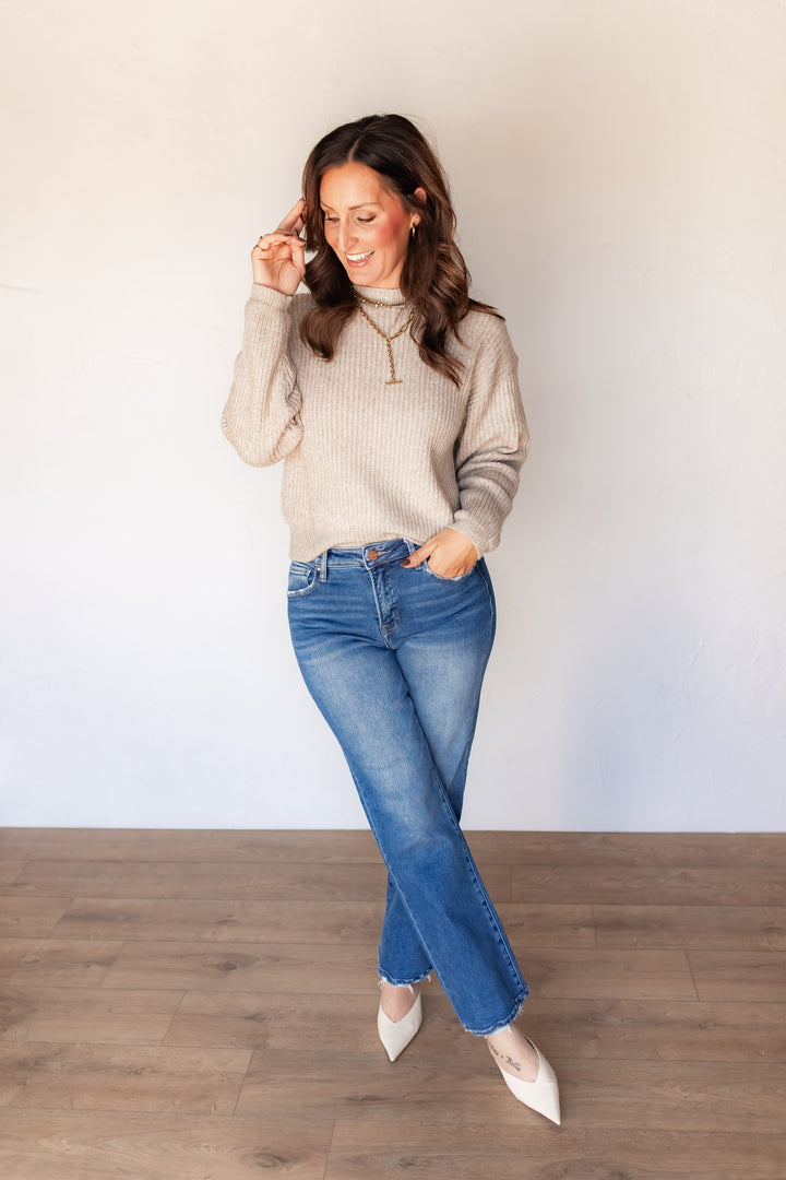 Oatmeal ribbed knit sweater styled with medium wash denim and white mules