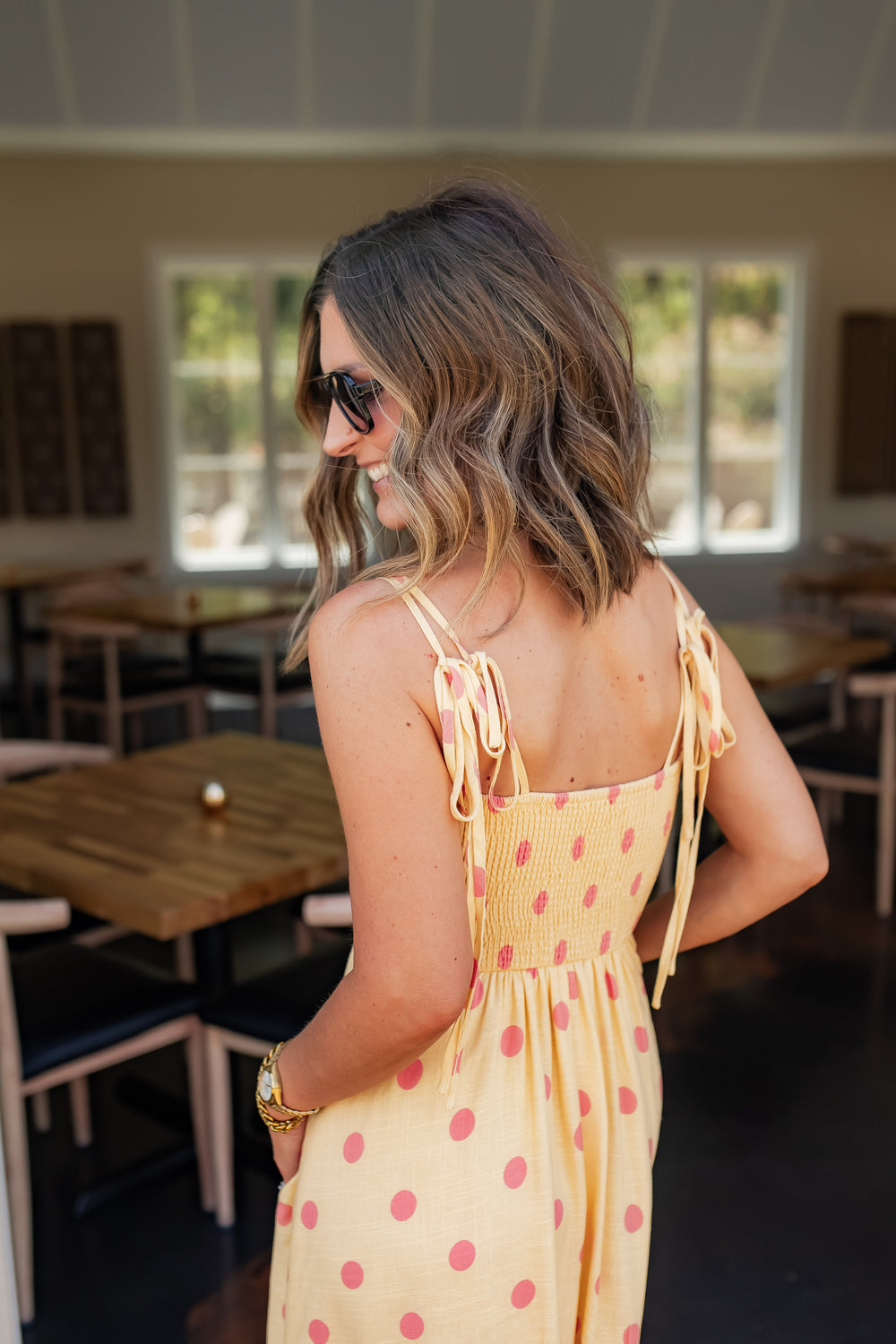 Back view of yellow polka dot maxi dress with adjustable tie straps and smocked detail