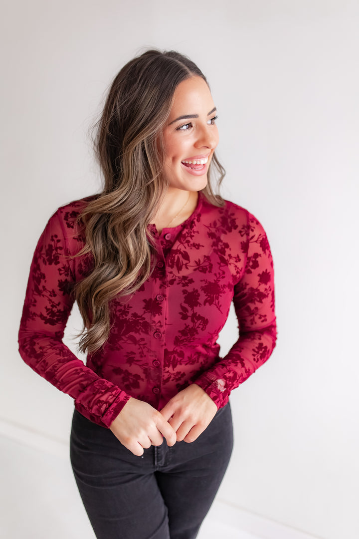 Woman wearing a red floral blouse against a white background