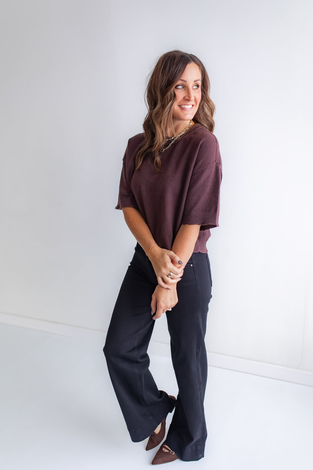 Model wearing brown short sleeve sweater with black jeans. 