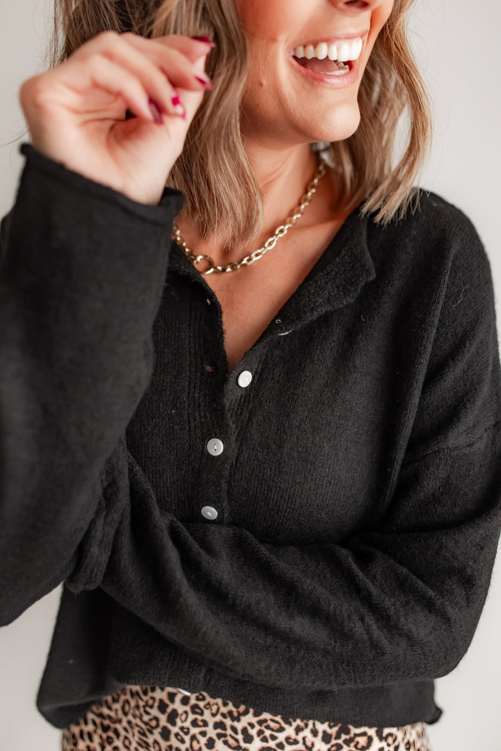Close up of a woman wearing a black long sleeve cardigan and leopard bottoms. 