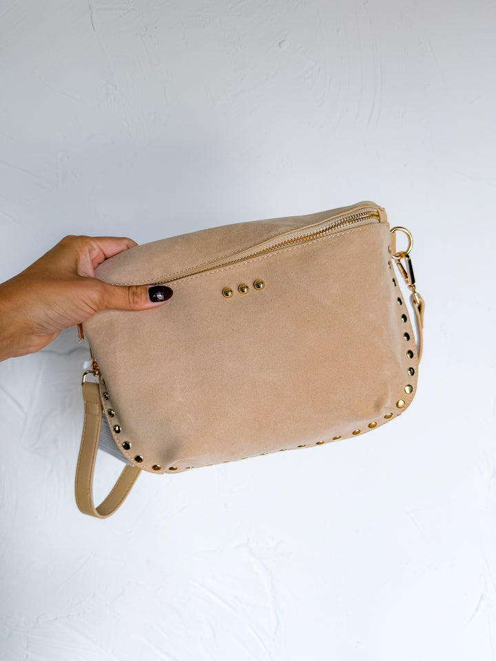 Close-up of taupe suede bag with gold stud trim and zip top closure