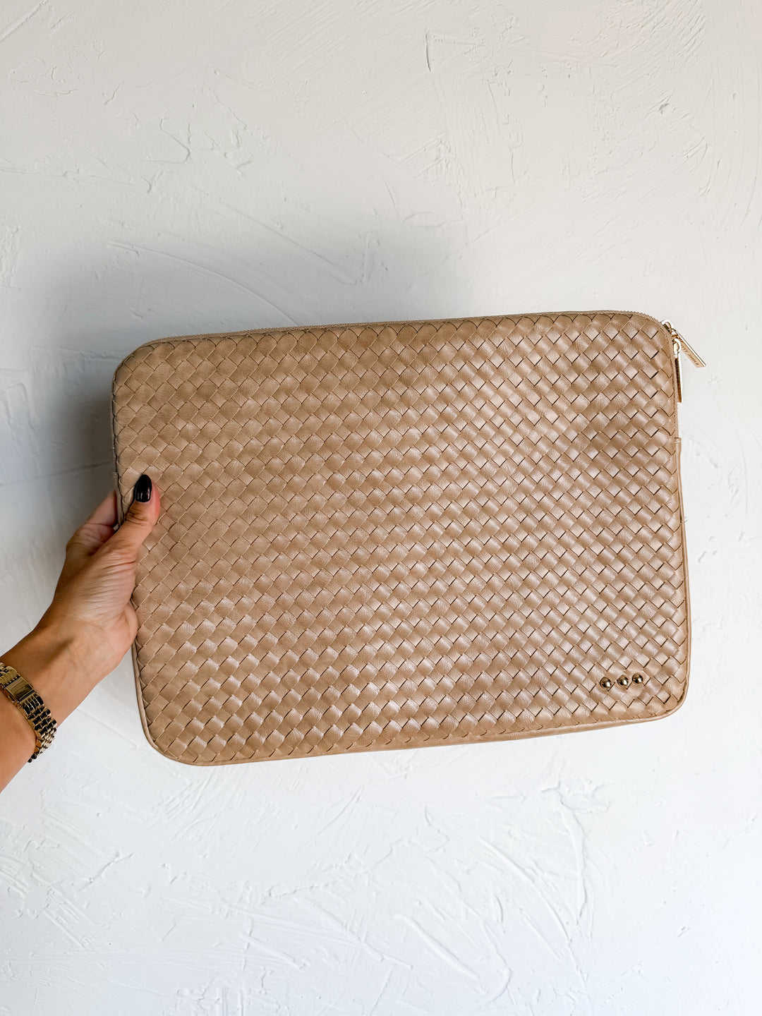 Taupe woven laptop sleeve with gold zipper pull held in hand