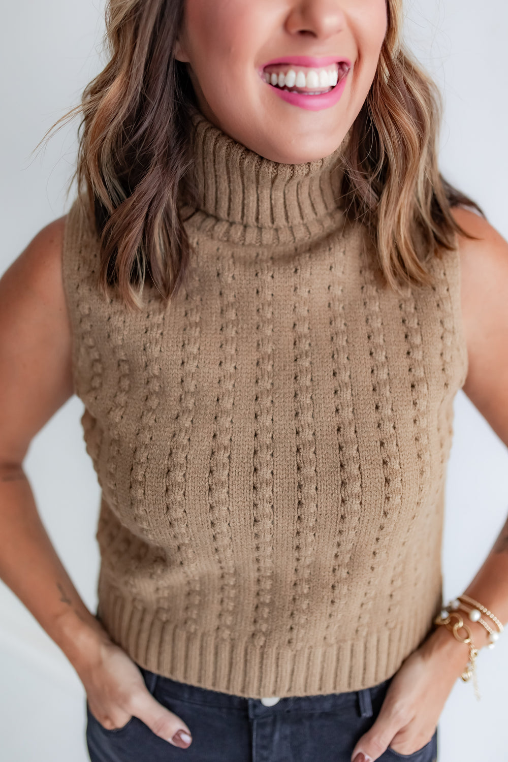Close up of woman wearing toffee sleeveless turtleneck sweater