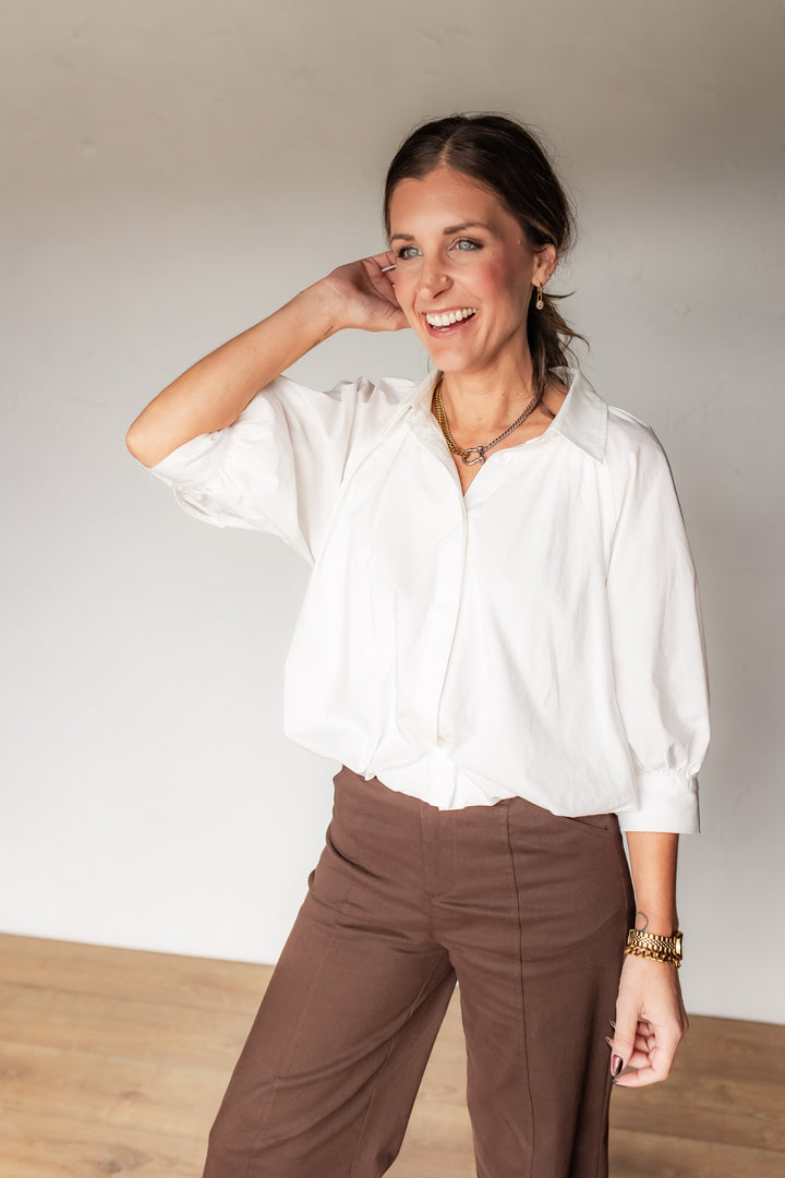 Woman wearing white poplin blouse with dropped shoulders and brown wide leg trousers