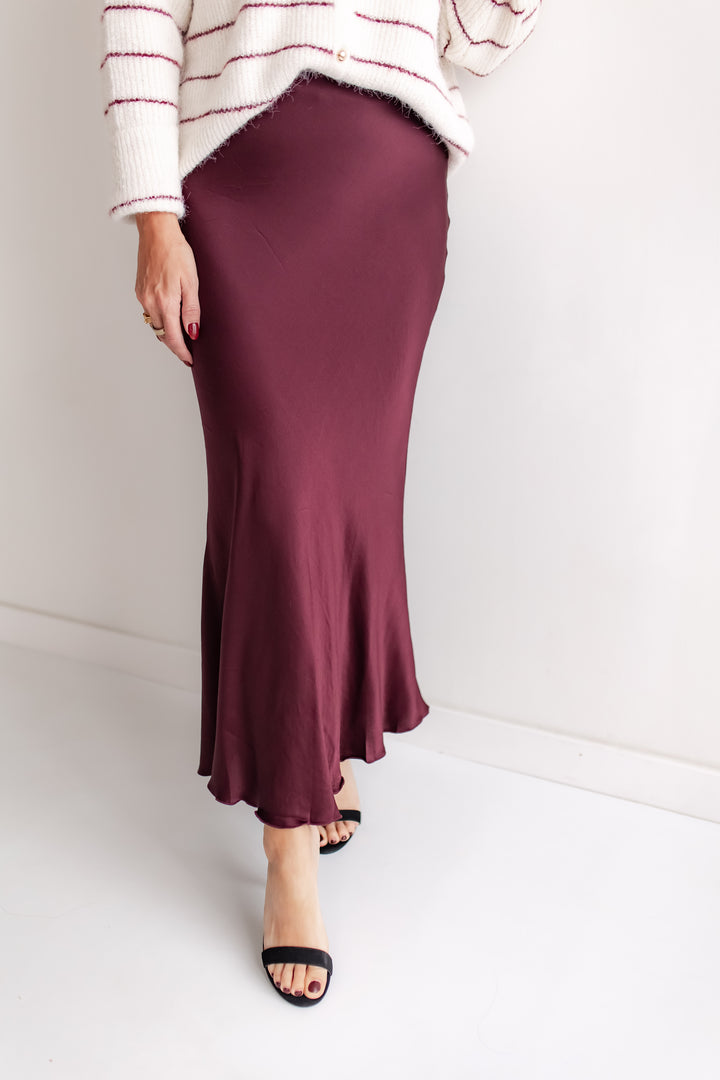 Person wearing a burgundy skirt and striped sweater on a white background